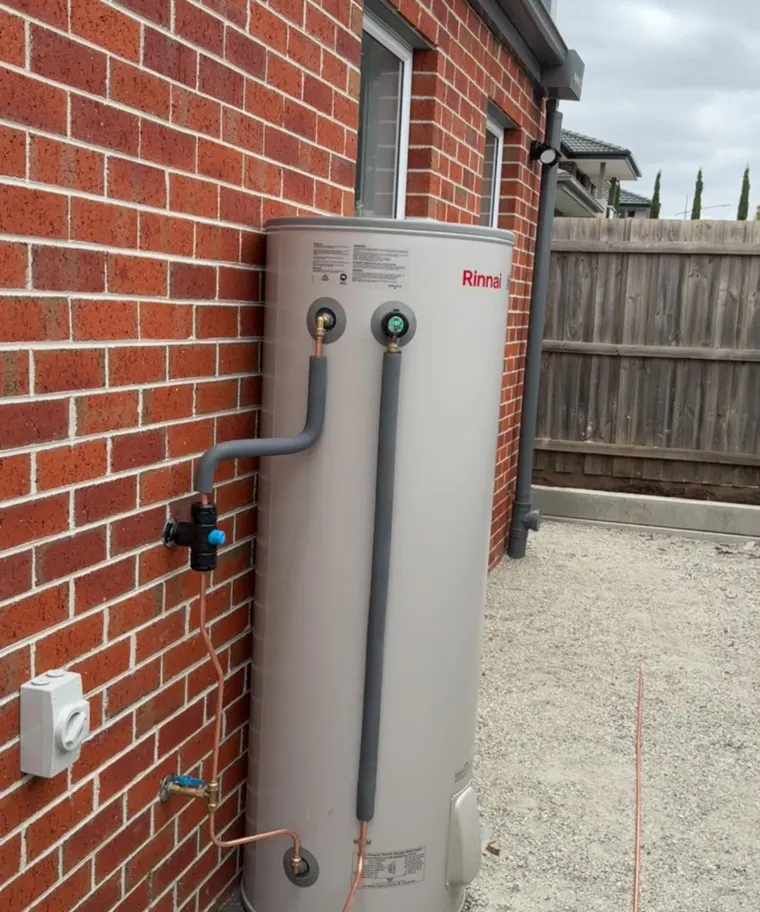 Storage hot water unit against a brick wall with insulated copper connections